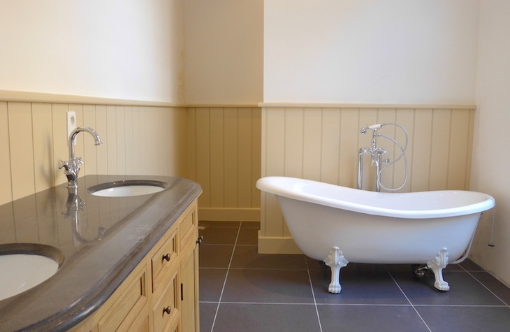 Nieuwe vloertegels, wanden bezetten en installatie sanitair met ligbad en wastafel