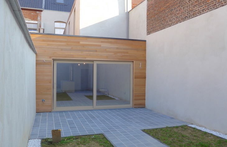 Nieuwe achtergevel in padoek hout afgewerkt met groot schuifraam dat uitgeeft op een totaal nieuw aangelegd terras. 